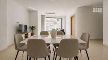 Un comedor moderno con una mesa rectangular, seis sillas, un televisor y una planta en maceta.