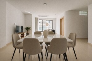 A modern dining area with a rectangular table, six chairs, a television, and a potted plant. - Spacieux 3 pieces a Kouba (Algiers)
