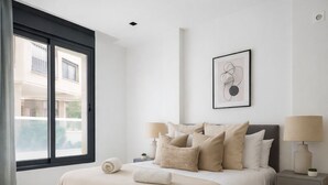 A bedroom with a bed, bedside tables, a window, and a wall-mounted picture. - Spacieux 3 pieces a Kouba (Algiers)