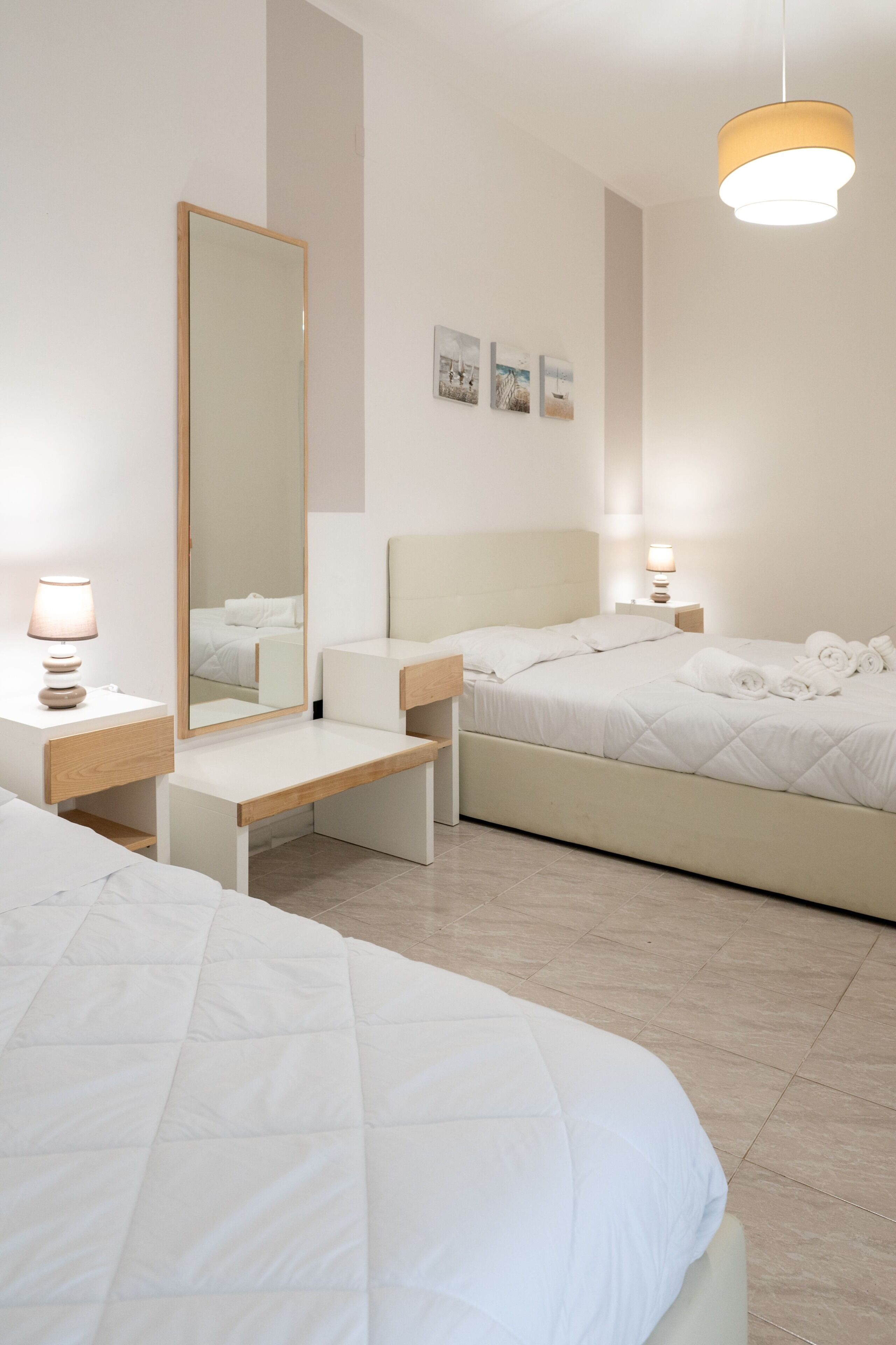 A hotel room with a bed, bedside table, lamp, and a large mirror.