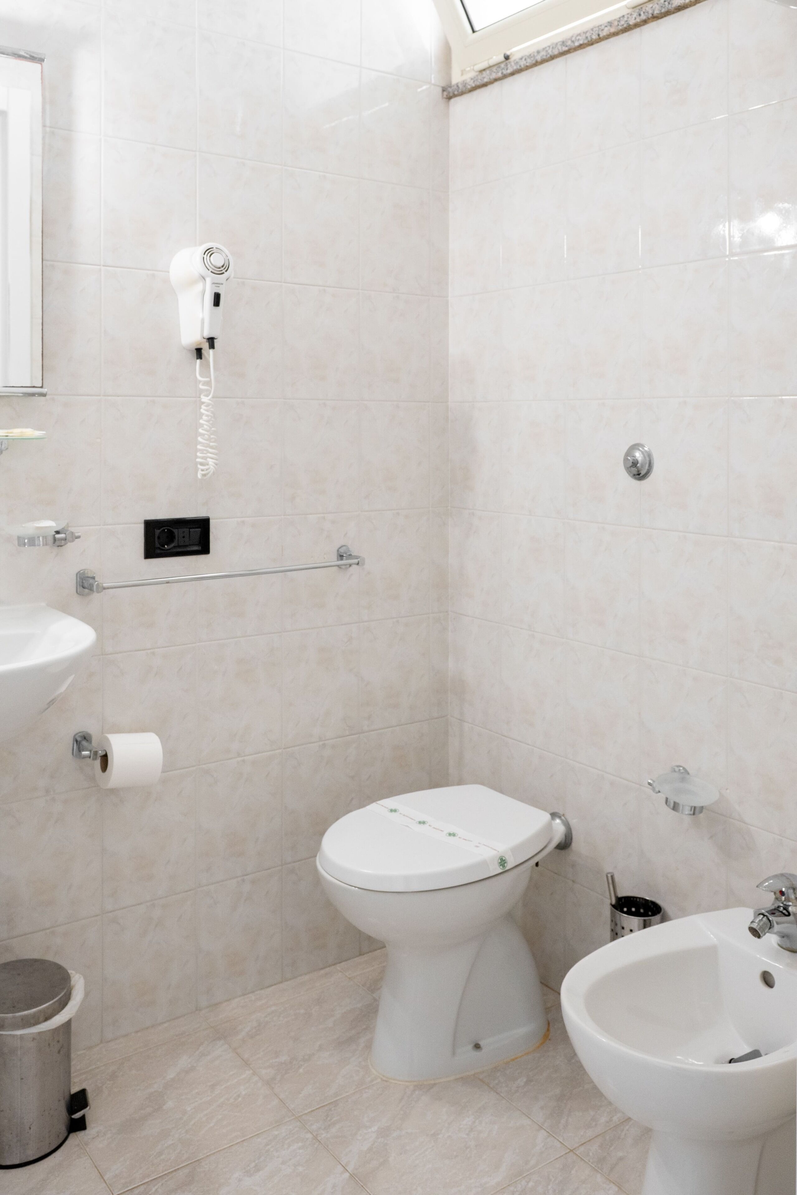 Un baño con inodoro, bidé, lavamanos y toallero.