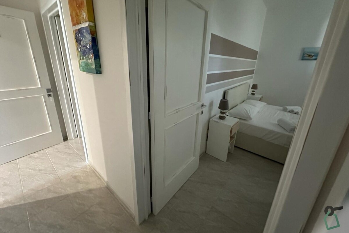 A bedroom with a bed, bedside tables, and a door.