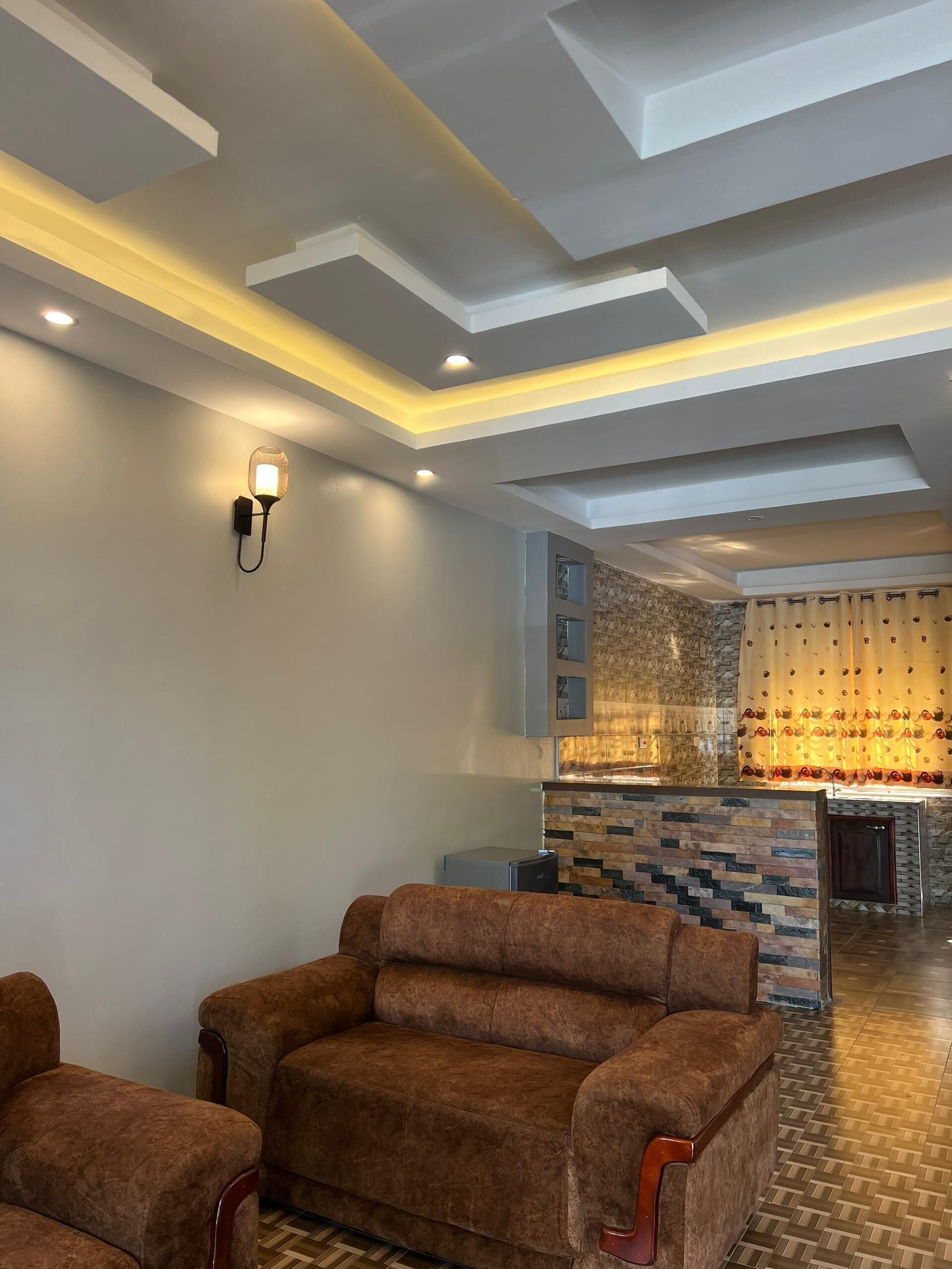 A modern living area with a sofa set, a stone accent wall, and recessed ceiling lighting.