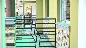 Um corredor com portão de metal, degraus verdes e parede revestida de azulejos.