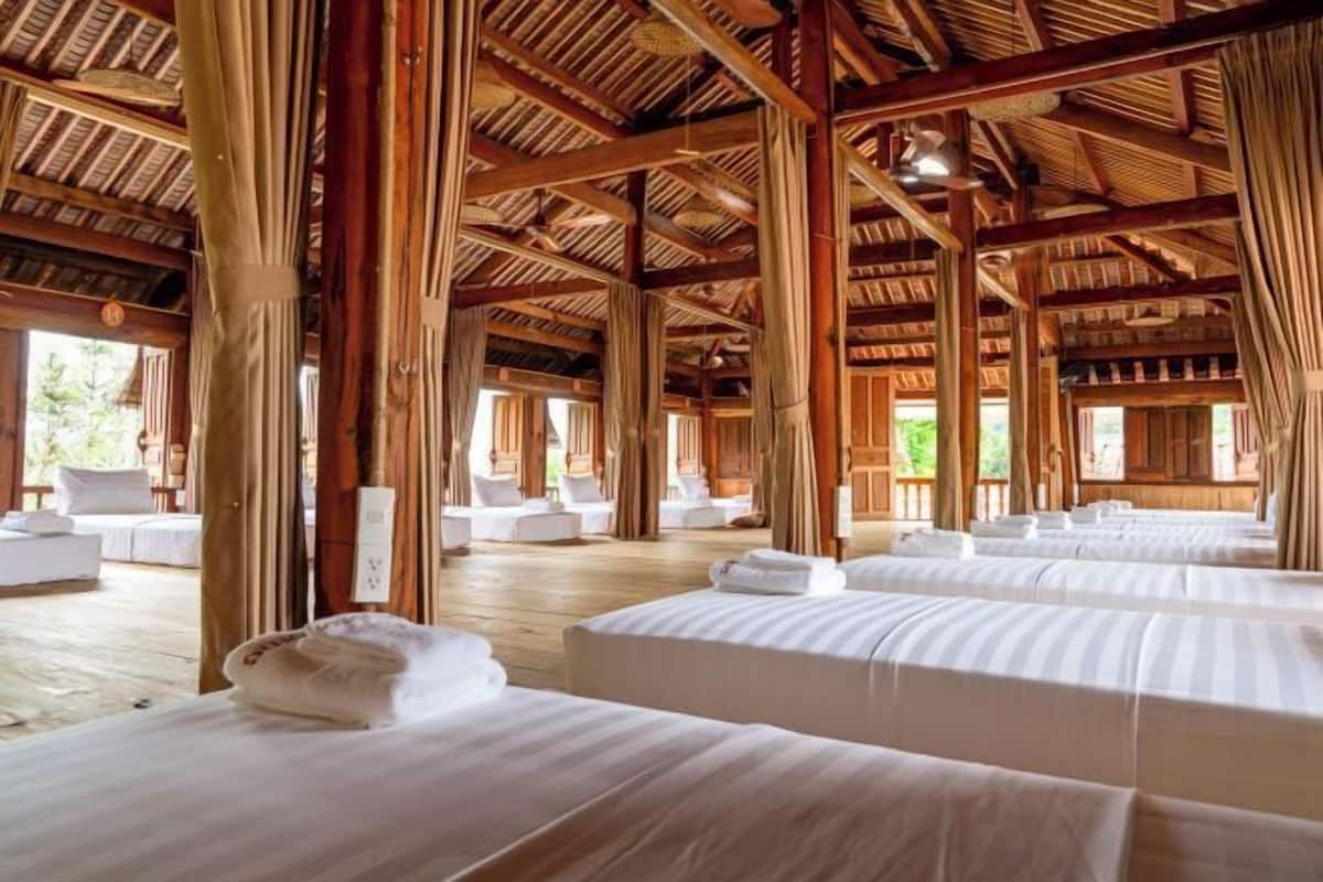 A hotel room with multiple beds, wooden beams, and large windows.