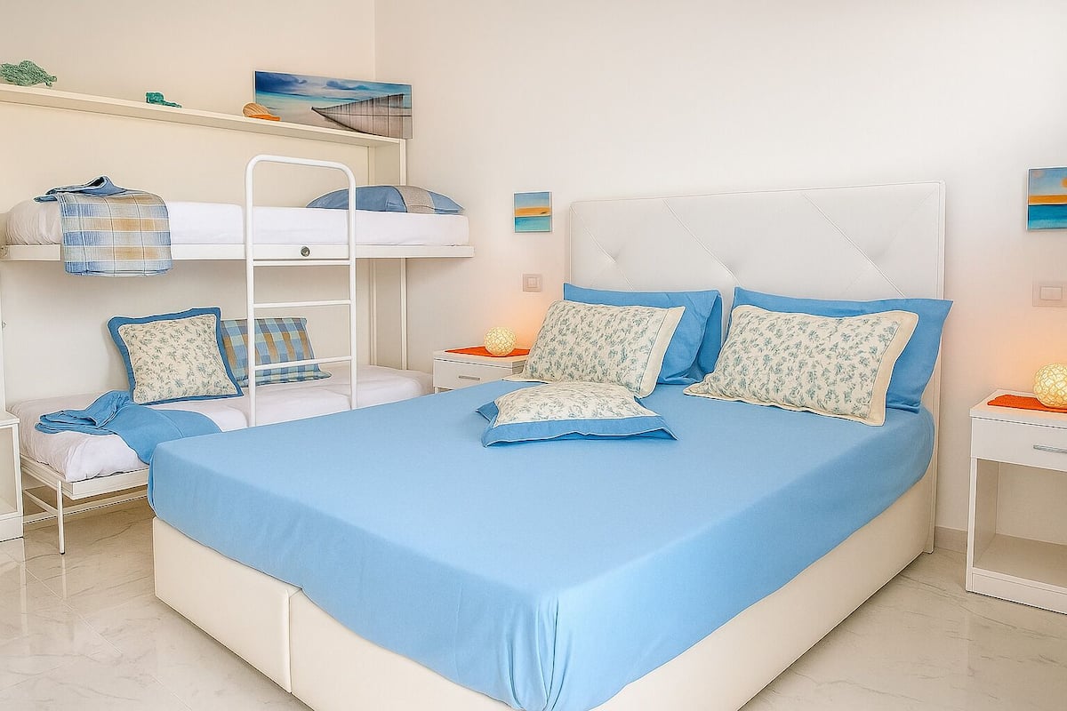 Una camera da letto con un letto grande, un letto a castello e una scrivania.