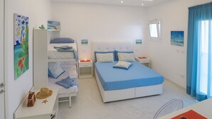 Een moderne slaapkamer met een groot bed, een kleiner bed en een bureau met een stoel. Er hangen schilderijen aan de muur en er is een raam met gordijnen.