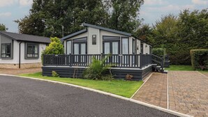 A single-story mobile home with a front deck, a paved driveway, and a well-maintained lawn.