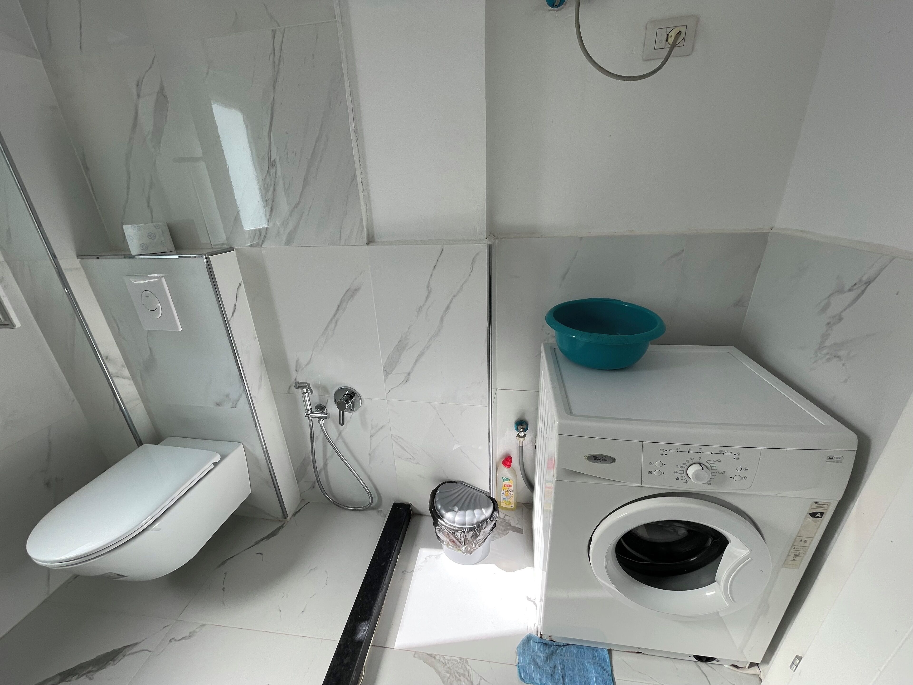 Un baño pequeño con inodoro, ducha y lavadora.