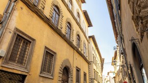 Una calle estrecha con edificios históricos, incluyendo un edificio con un letrero con el número 19, ventanas en arco y una señal de parada.