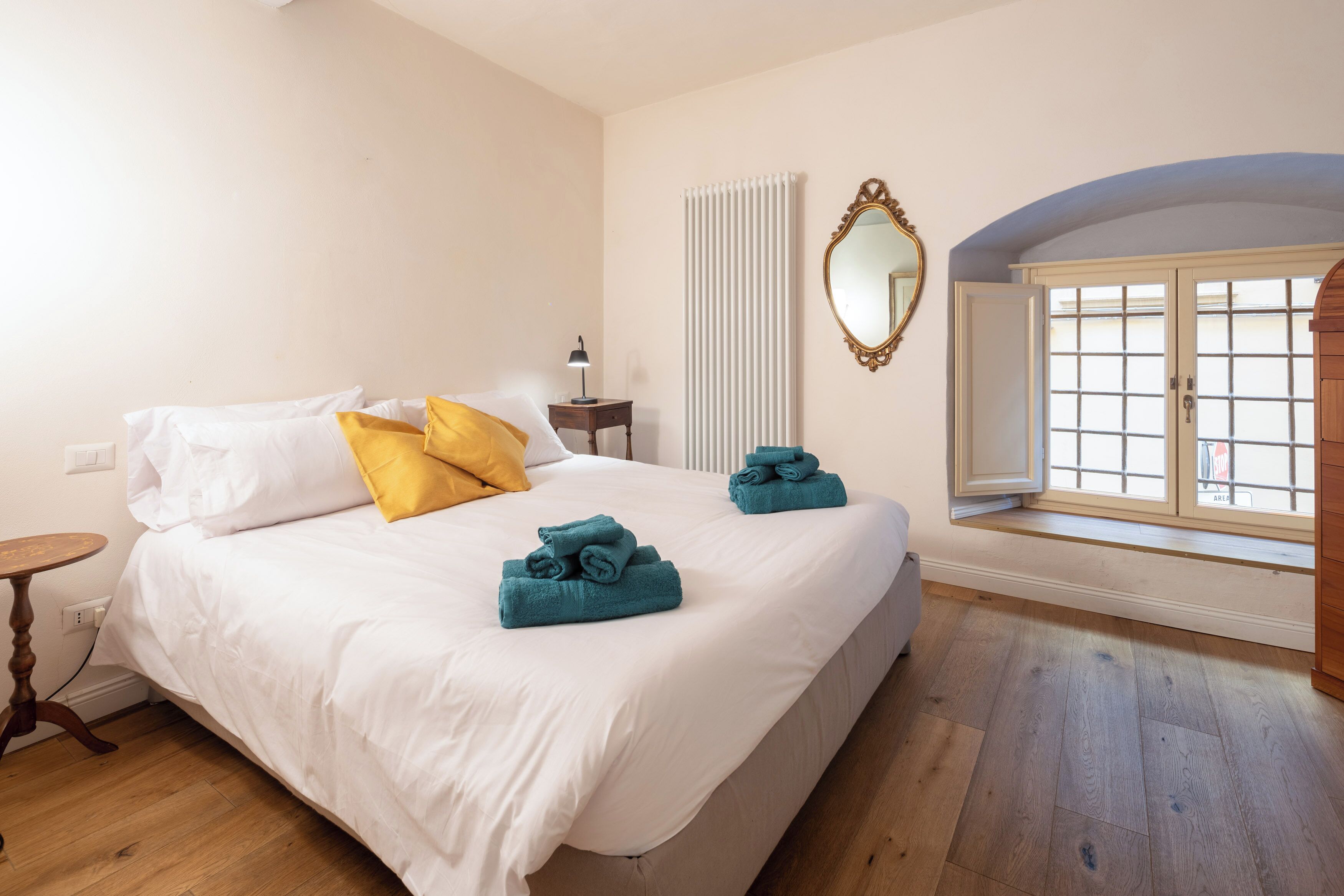Ein Schlafzimmer mit einem großen Bett, einem Nachttisch, einem Spiegel und einem Fenster mit Blick.