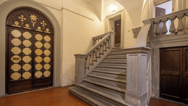Una imponente escalera con barandales ornamentados y un puerta grande y decorativa con diseños geométricos.