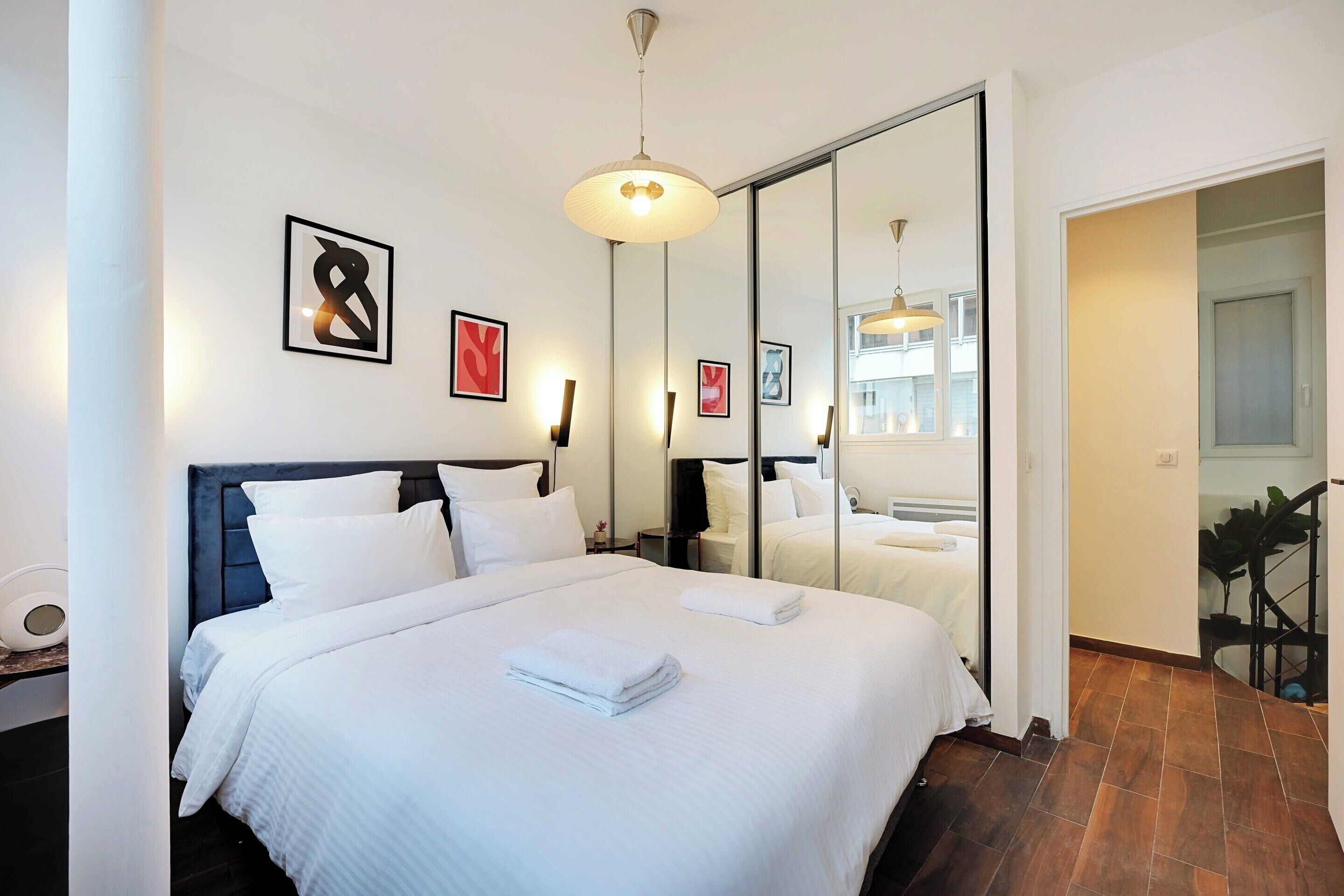 Una habitación de hotel moderna con una cama grande, un espejo y obras de arte en las paredes.