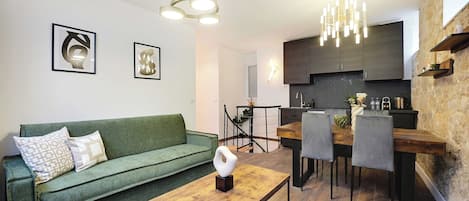 Ein modernes Wohnzimmer mit einem grünen Sofa, einem Holztisch und einem Essbereich mit Stühlen und einem Tisch.