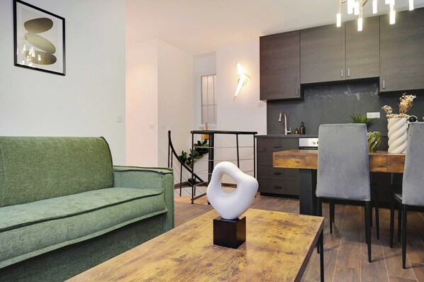 A modern living room with a green sofa, a wooden coffee table, and a white abstract sculpture.