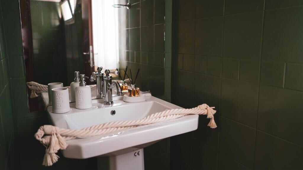 A bathroom with a white sink, a mirror, and a towel rack.