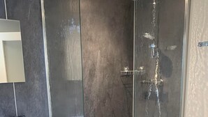 A modern bathroom with a glass-enclosed shower, a vanity with a mirror, and a red towel.