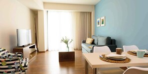A modern living room with a sofa, television, dining table, and chairs. - Elounda Colour Apartments (Elounda)