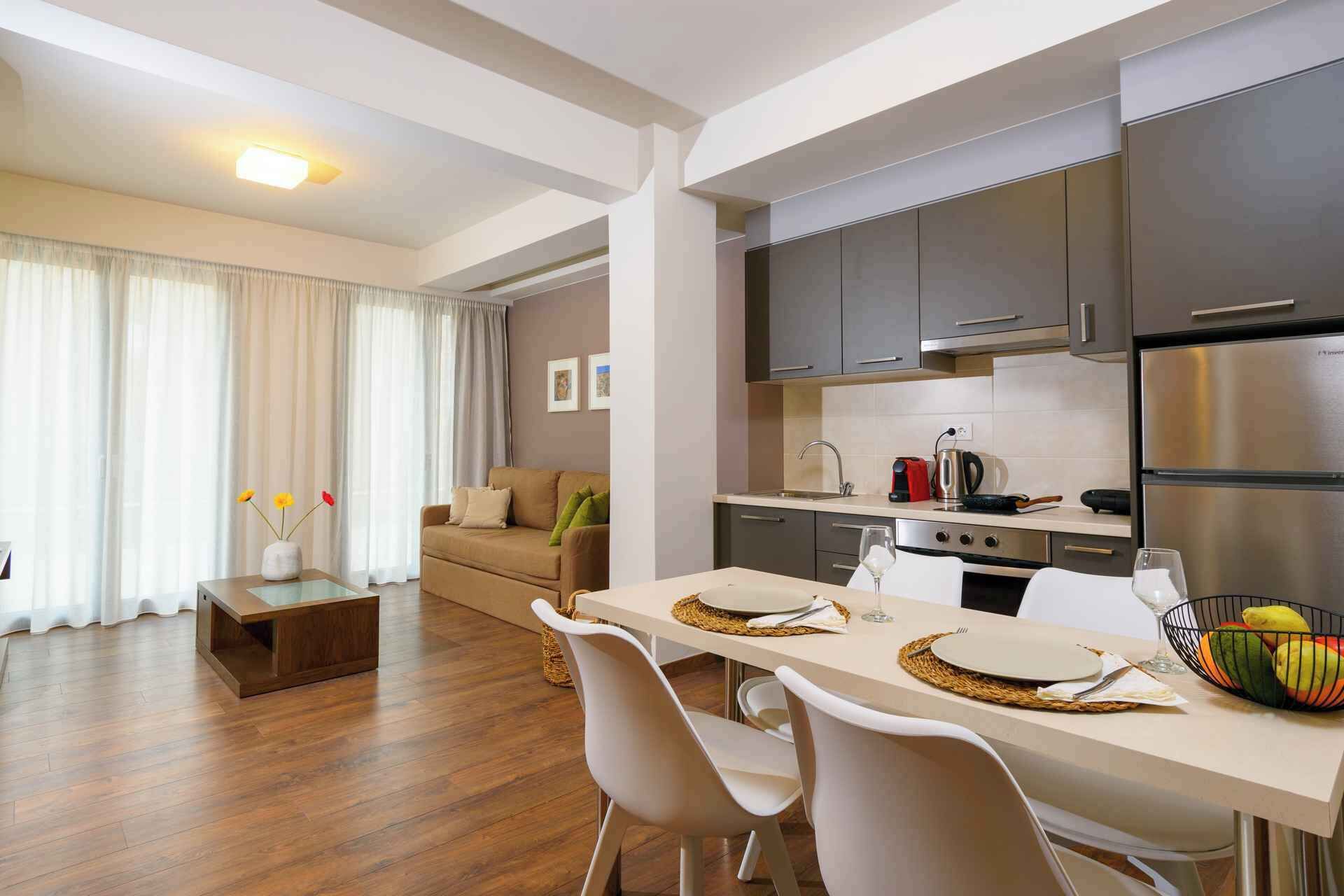 A modern kitchen with dark cabinets, a stainless steel refrigerator, and a dining area with a table set for two.
