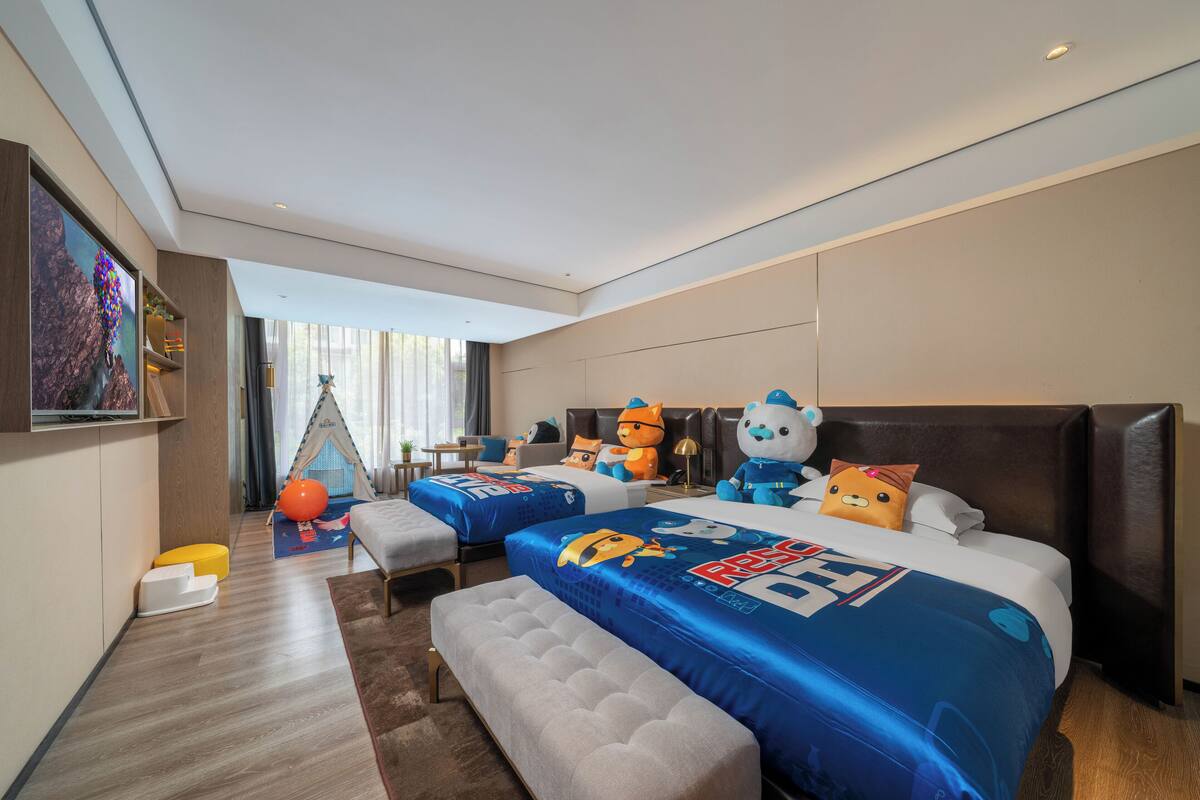 Una habitación de hotel con dos camas, una tienda de juegos y juguetes de peluche.