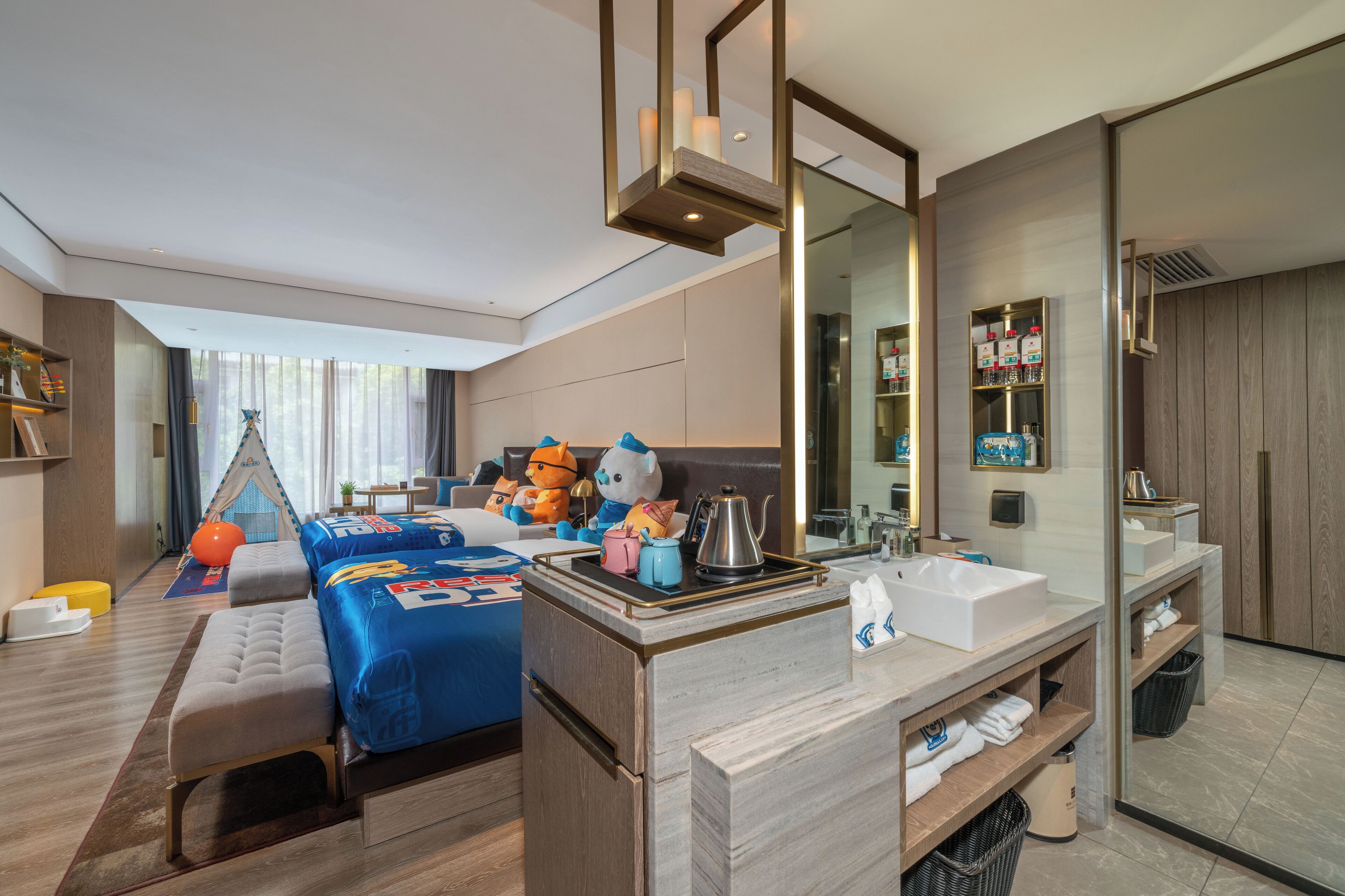 A modern hotel room with a large bed, a desk, a mirror, and a bathroom with a sink and shelves.