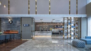 Een moderne lobby met een receptiebalie, zithoek en een boekenkast.
