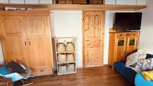 Une pièce chaleureuse avec une armoire en bois, un téléviseur posé sur un meuble, un canapé bleu et un fauteuil à bascule.
