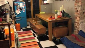 Une cuisine compacte comprenant un réfrigérateur, une table à manger et un tapis rayé aux couleurs vives.