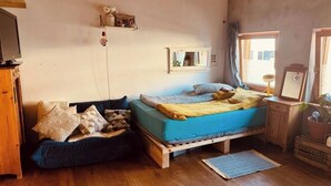 Une chambre confortable avec un lit, un banc en bois, une petite table et un miroir.