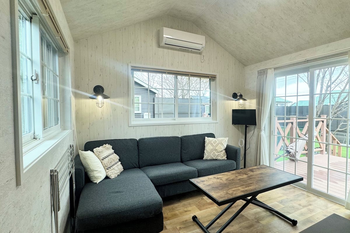 A cozy room with a grey sectional sofa, a wooden coffee table, and a large sliding glass door leading to a deck.