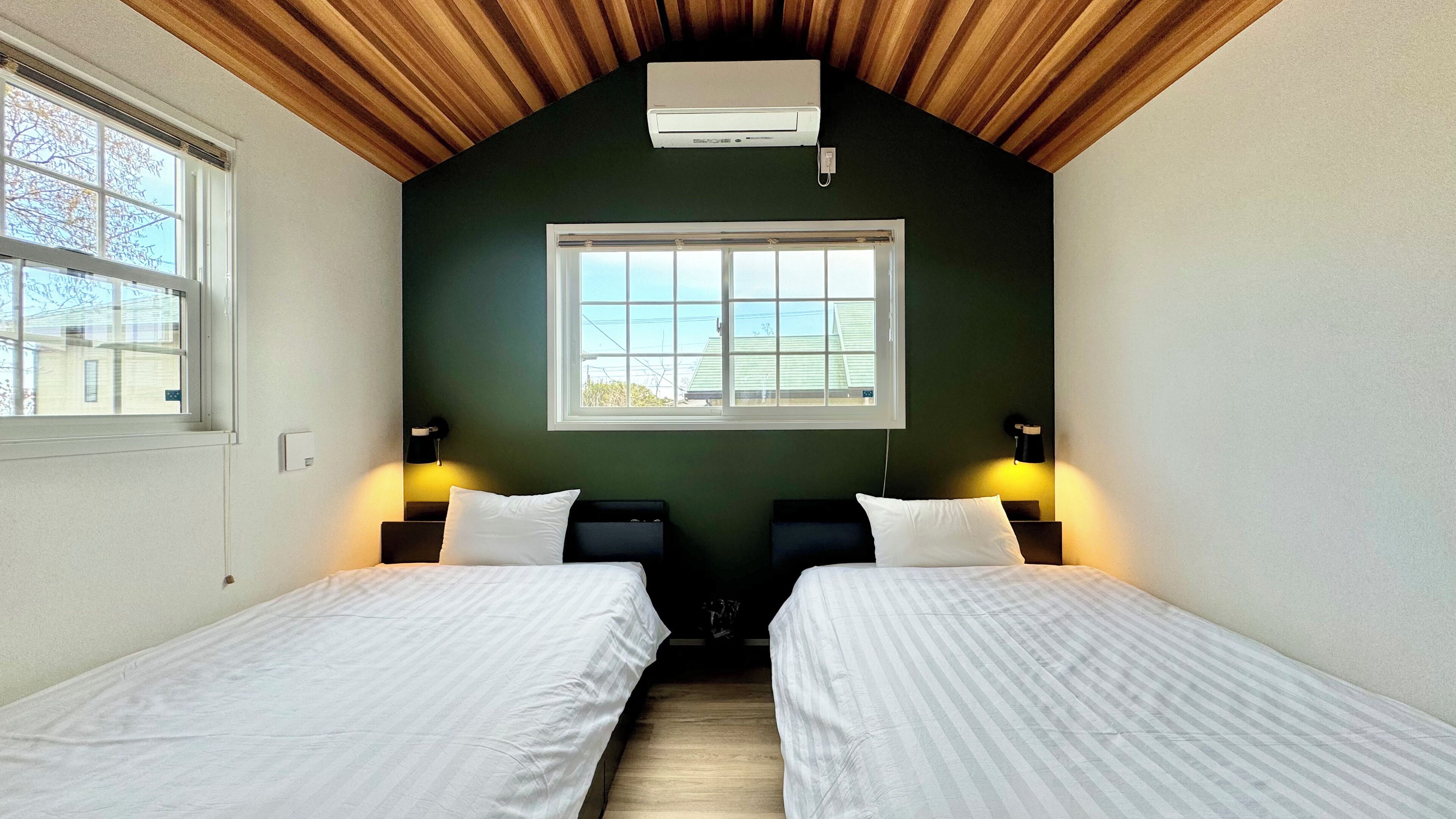A room with two beds, a window, and an air conditioner on the wall.