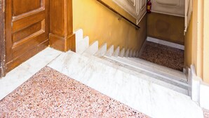 A wooden door, a marble staircase, and a fire extinguisher in a hallway. - Metro Università Apartment by Wonderful Italy (Naples)