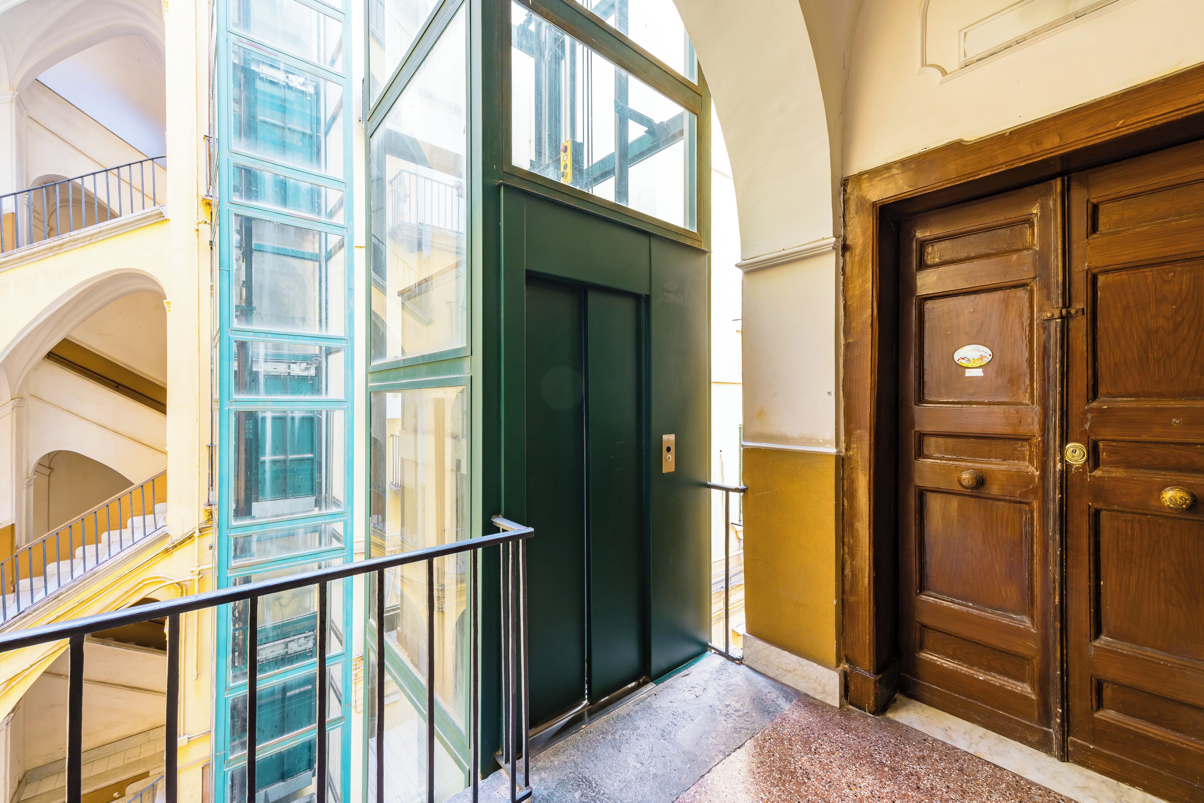 Un edificio con una escalera, un ascensor verde y una puerta de madera.