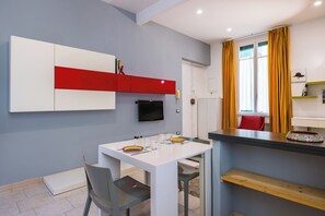 Una cocina moderna con una mesa blanca, sillas y un estante rojo.