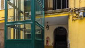 A building entrance with a green door, a staircase leading to a balcony, and a fire extinguisher on the wall. - Metro Università Apartment by Wonderful Italy (Naples)