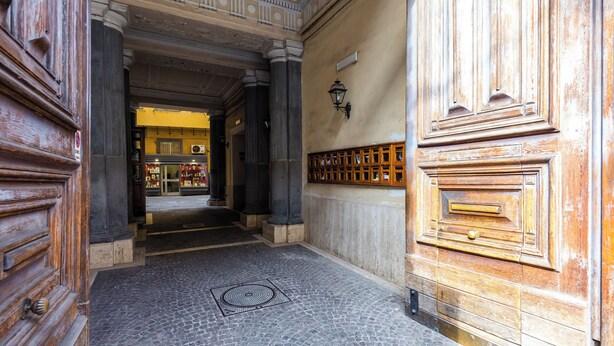 A cobblestone floor, wooden doors, and a stone wall with a metal grate. - Metro Università Apartment by Wonderful Italy (Naples)