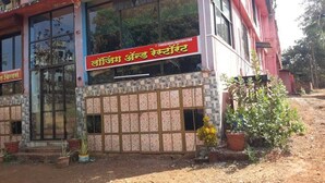 Un bâtiment avec une enseigne en langue locale, une entrée fermée par un portail et des plantes en pot à l’extérieur.