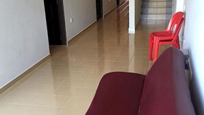 En gang med en rød stol, en rød sofa og et flisegulv.