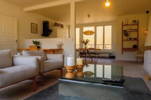 A modern living room with a sofa, a coffee table, and a dining area with a table and chairs.