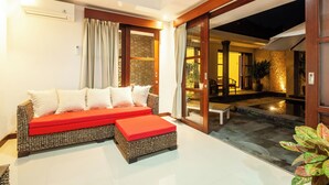 A modern living room with a sofa, ottoman, and a glass door leading to an outdoor area. - 9BR Private Pool Sanur Beach Villa (3units villa) (Bali)