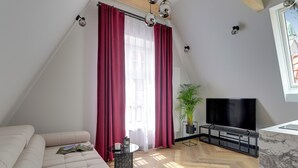 Una sala de estar moderna con un sofá, un televisor, una mesa de centro y una planta en maceta.