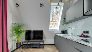 Una cocina moderna con un ventanal grande, una planta en maceta, un televisor de pantalla plana y un fregadero con un cuenco de fruta.