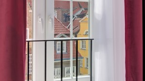 Una ventana con vista a un edificio que tiene una torre con reloj y numerosas ventanas.