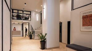 Un interior moderno con suelo en espiga, un mostrador de recepción, una escalera y una obra de arte enmarcada en la pared.