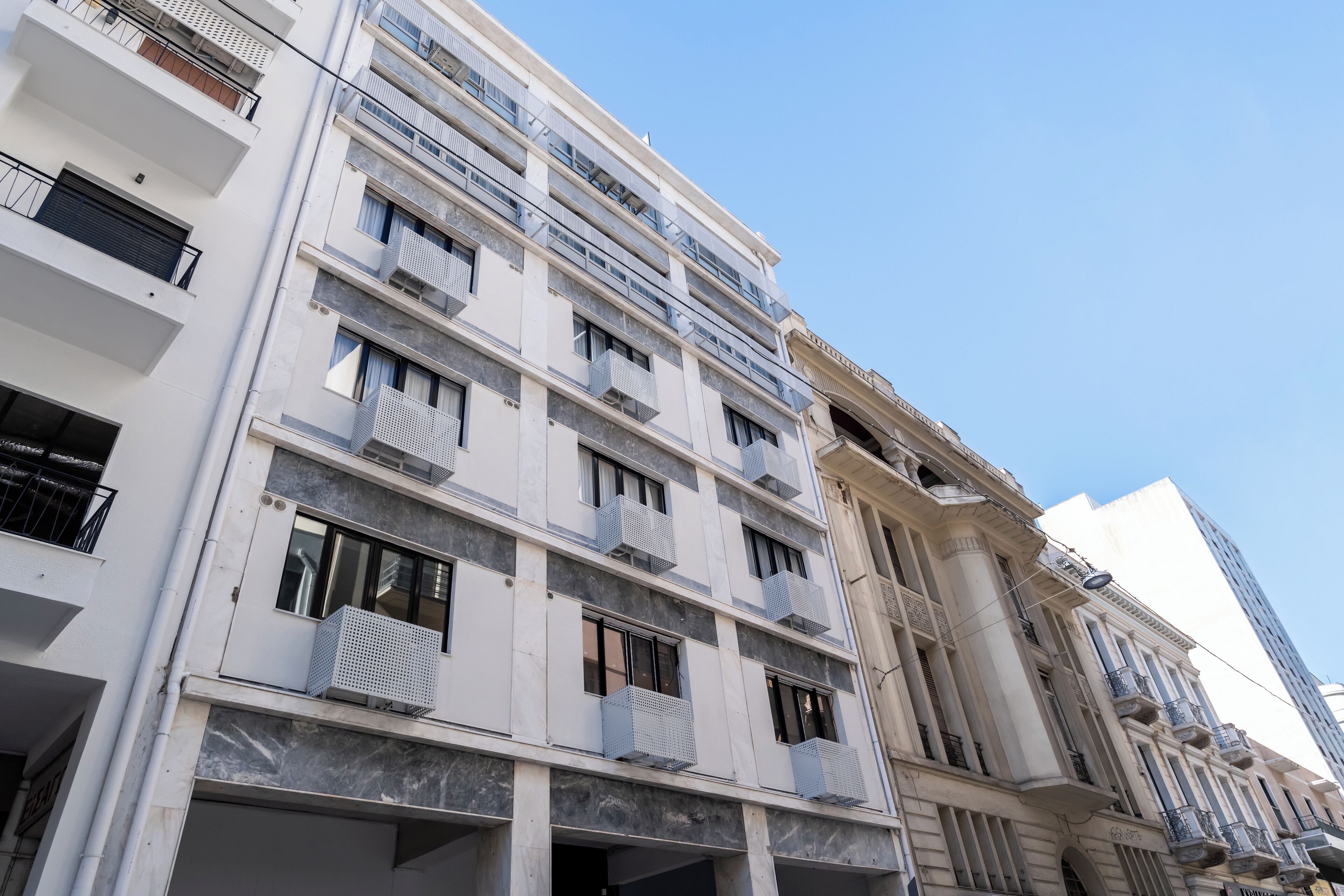 A multi-story building with balconies, large windows, and a classical architectural style.