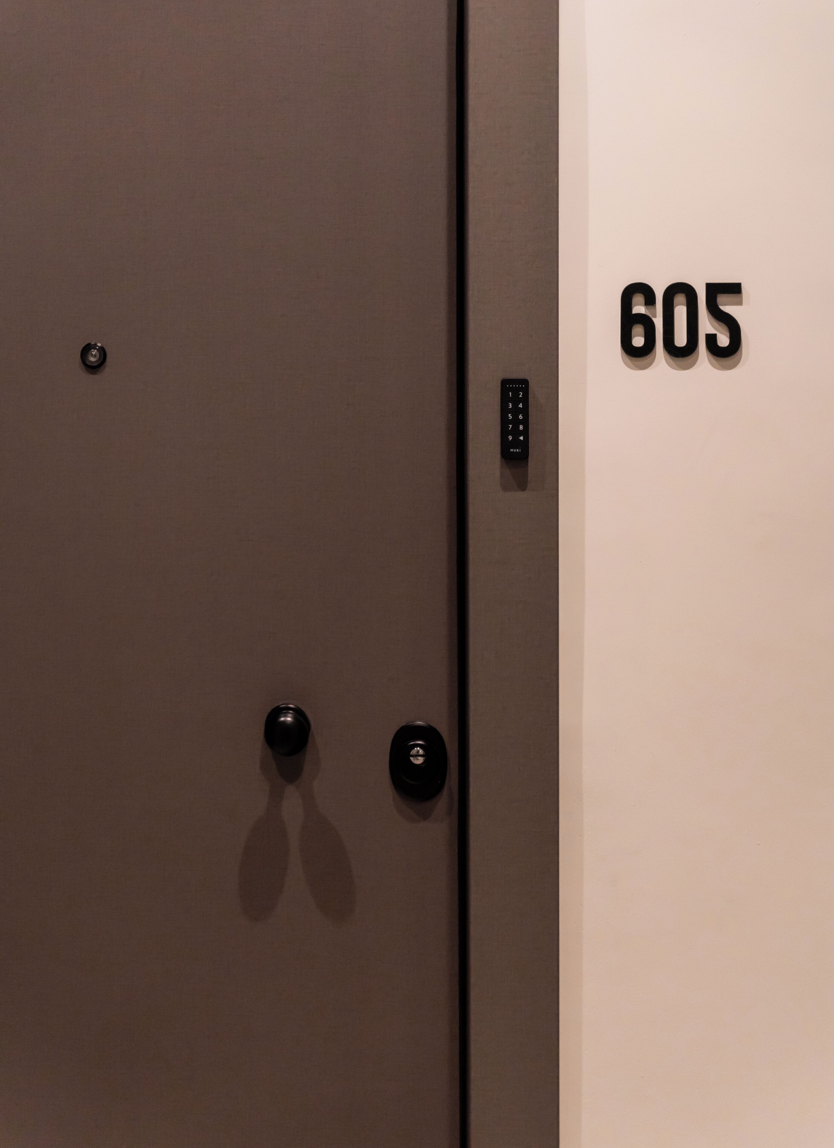 A door with a keypad and a number "605" on the wall.