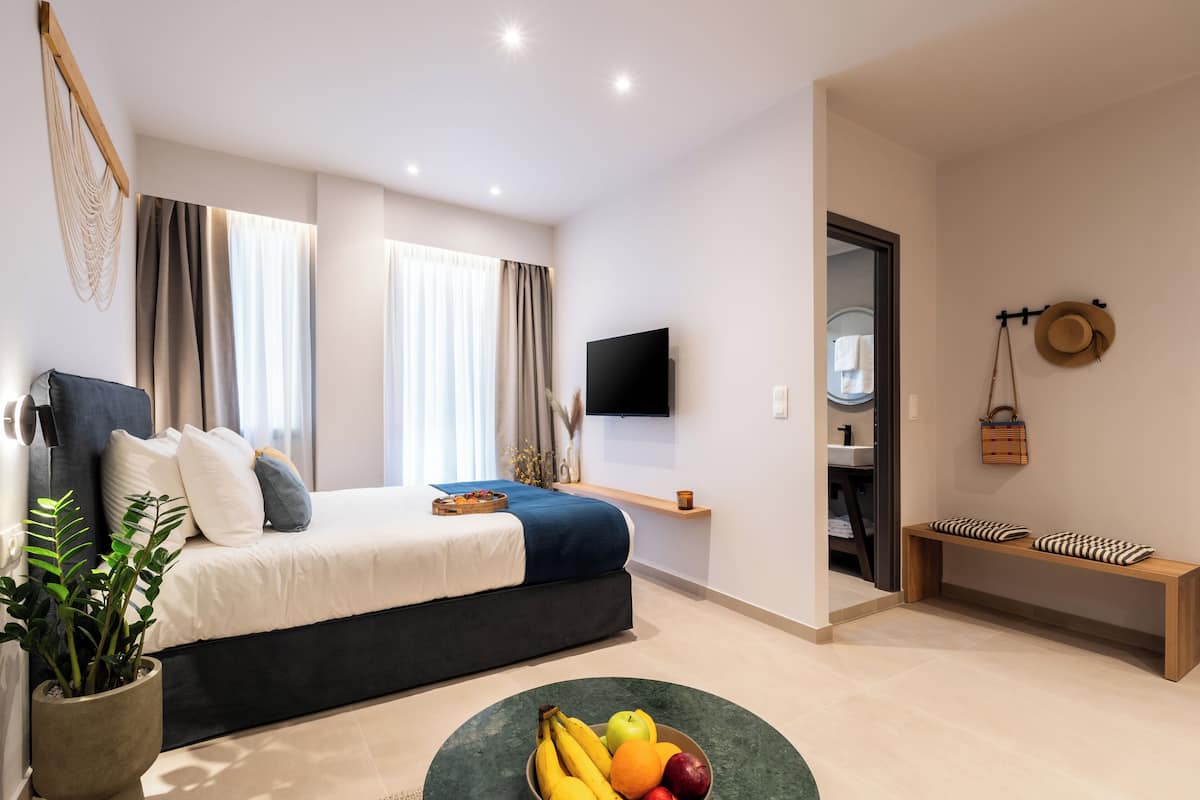 A modern bedroom with a bed, bedside table, TV, and a fruit bowl on the floor.