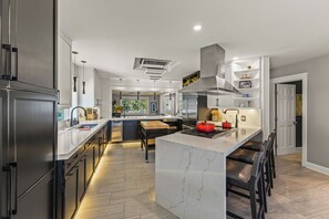 A modern kitchen with a central island, stainless steel appliances, and a built-in oven.