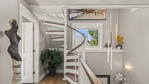 Eine Wendeltreppe mit weißen Geländern und Holzstufen, die zu einer Aussichtsplattform mit Blick ins Freie führt.