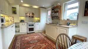 Una cocina con armarios blancos, estufa, lavamanos y ventana con vista a edificios.